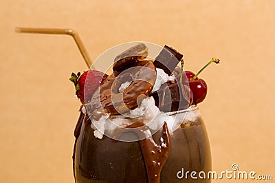 Close up of chocolate indulgent extreme milkshake with brownie cake, strawberries, cherries, and a plastic straw with Stock Photo