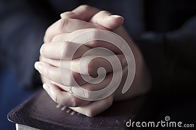 Women Folding Hands over a Bible Stock Photo