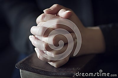 Folding Hands over a Bible Stock Photo