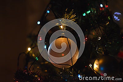 Close-up of a Christmas bauble ornament and colorful lights on a fir tree Stock Photo