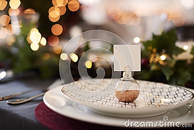 Close up of Christmas table setting with bauble name card holder arranged on a plate and green and red table decorations Stock Photo