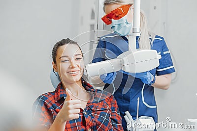 Close up of client smiling and showing thumb up while dentist holding x-ray Stock Photo