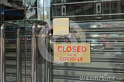 Close-up on a closed sign in the window of a shop displaying the message `Closed due to Covid-19 Stock Photo