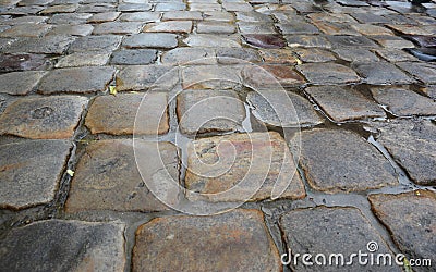 A close-up of a cobbled street in an old town. Wet cobbled road background Stock Photo