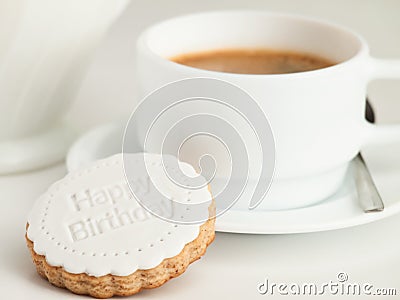 Close up of coffee cup and fondant covered cookie. Happy birthday decoration on top. Stock Photo