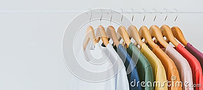 Close up collection of colorful t-shirts hanging on wooden clothes hanger in closet or clothing rack over white background, copy Stock Photo