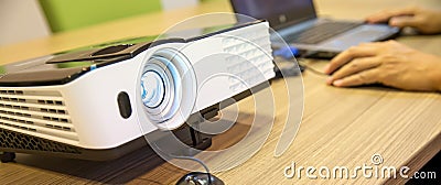 Close up computer projector on meeting tables with laptop setup at boardroom Stock Photo