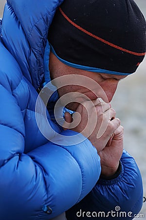 Close up of a concentrated and pensive mountain climber in thick down jacket lost in thought Stock Photo