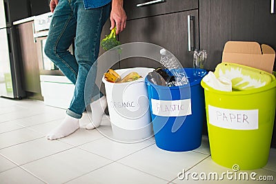 Close-up concept. Sort garbage at home. There are three buckets for different types of garbage. Guy sorts waste in the Stock Photo
