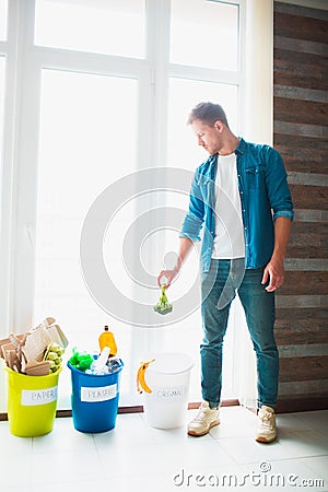 Close-up concept. Sort garbage at home. There are three buckets for different types of garbage. Guy sorts waste in the Stock Photo