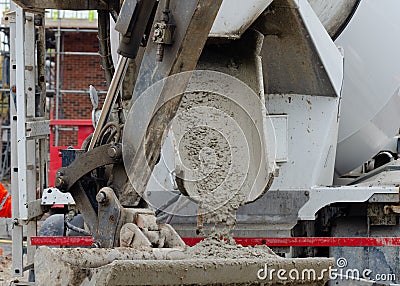 Close up of concrete flowing into excavator bucket from delivery vagon Stock Photo