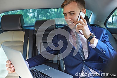 Confident businessman talking on mobile phone sitting in the back seat of a car Stock Photo