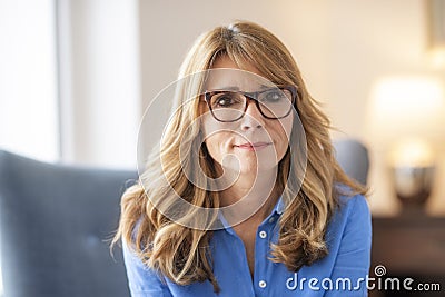 Close-up of confident middle aged woman looking at camera while relaxing indoor Stock Photo