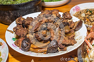 Close-up on cooked duck with mushrooms. Southern Chinese festivity rural food on bowls and plates at a wooden table Stock Photo