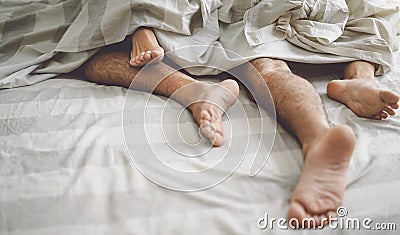 Close up couple feet having sex in bed - Young lovers intimate and passionate moments under white sheets in bedroom Stock Photo