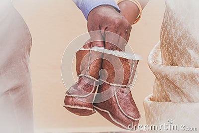 close up of couple hands holding a pair of baby boots Stock Photo