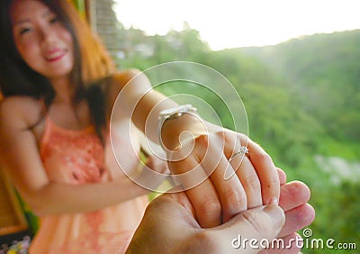 Close up couple hands man holding Asian happy fiance hand with diamond engagement ring on her finger after wedding proposal at Stock Photo