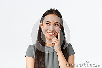 Close-up of creative and dreamy smiling pretty asian woman thinking, imaging something interesting in mind, looking left Stock Photo