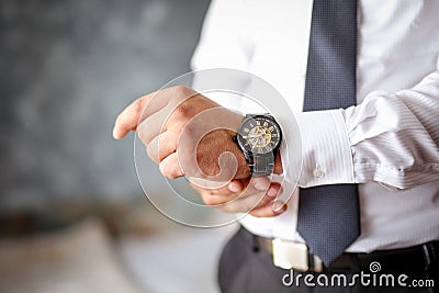 A close-up of a cropped frame of a man in an expensive classic costume looks at his watch. Stock Photo