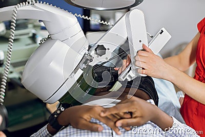 Close up cropped image of lying African man patient having procedure of lithotripsy. Hands of female doctor working with Stock Photo
