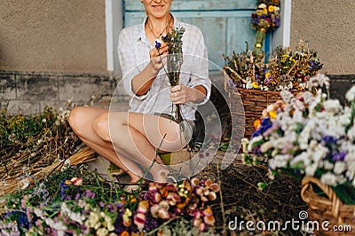 Close-up, cropped photo. A female florist sits in the country amidst a harvest of dried flowers and makes a beautiful holiday Stock Photo