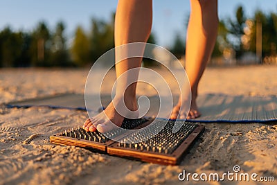 Close-up cropped shot of feet unrecognizable woman stepping on Sadhu Nail board during concentration meditation practice Stock Photo