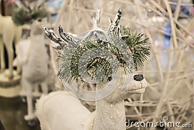 Close-up cropped white sparkly reindeer Christmas decoration with garland of snow covered greenery around horns - selective focus Stock Photo