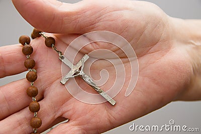Close-up of the crucifix of a wooden rosary in the hand of an elderly woman Stock Photo