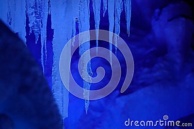 CLOSE UP: Crystal clear rods of ice hang from the ceiling of a frozen cavern. Stock Photo