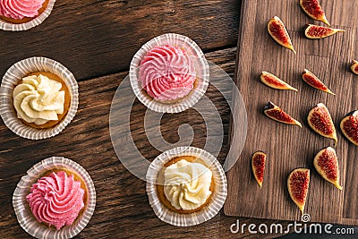 Close up cupcakes with cream and figs on wooden background top view. Vanilla muffins Stock Photo