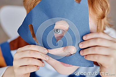 Close-up of cute blueeyed little boy covering face with blue paper mask Stock Photo