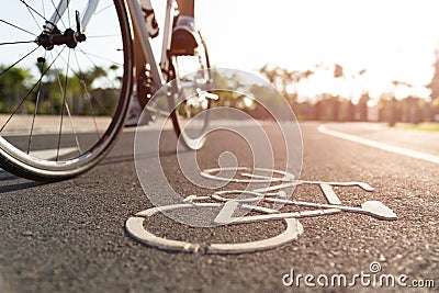 Close up cycling logo image on road with athletic women cyclist legs riding Mountain Bike in background at the morning Stock Photo