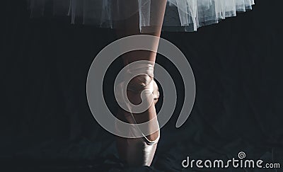 Close-up of dancing legs of ballerina wearing white pointe on a black background Stock Photo