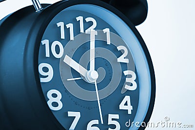 Close up of dark blue color vintage alarm clock on white wall, t Stock Photo