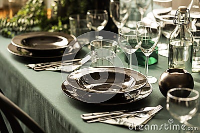 Close-up of a dark dining set on an elegant table with green cloth in a restaurant interior. Real photo Stock Photo