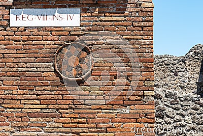 Close-up on stone sculpture representing a flower decorating old bricks wall of house in ruins in Pompei Stock Photo