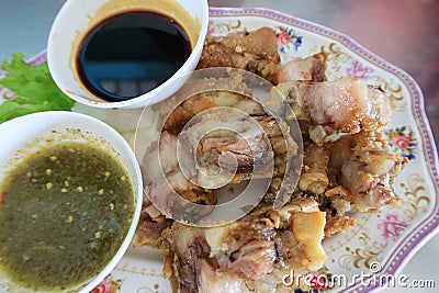 Close-up of deep-fried pork knuckle with dipping sauces and sauces, a popular Thai local dish. Stock Photo