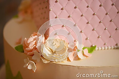 Icing floral decoration on a tiered cake, embellished with velvet pastel pink icing, sugar flowers and silver edible pearls Stock Photo