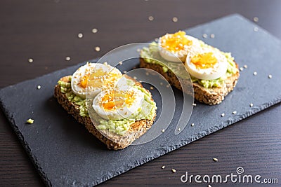 Close-up of delicious avocado toast topped with sliced boiled eggs and sesame seeds Stock Photo