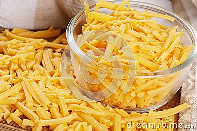 Close up of delicious Grated Cheddar Cheese on wooden background Stock Photo