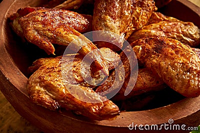 Close up of delicious grilled chicken wings in wooden bowl on wooden table. Stock Photo