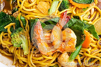 Close up delicious yellow fried noodles with soy sauce, prawns, vegetables and mushrooms. Thai stir-fried noodles Pad See-Ew. To Stock Photo