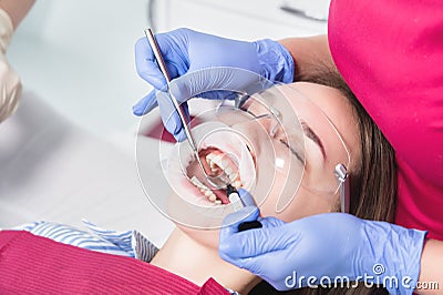 Close-up of a dentist applying polymer from a syringe to the inside of a young patient`s front tooth in a dental office Stock Photo