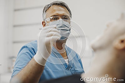 Close up of dentist in blue uniform checking up client teeth health condition. Stock Photo