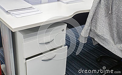 Desk drawer and office desk with jacket on chair Stock Photo