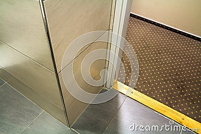 Close-up detail, corner of modern luxurious empty bathroom with floor to ceiling marble ceramic light beige shiny tiles. Professio Stock Photo