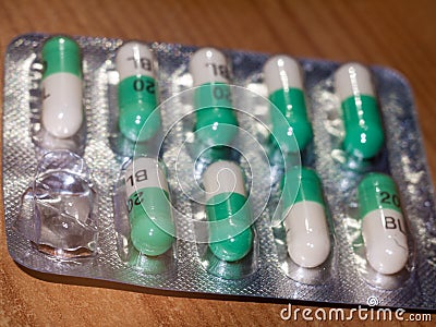 close up detail of foil packet of green and white prozac painkiller tablets on table surface Editorial Stock Photo