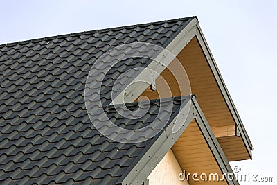 Close-up detail of new modern house top with shingled green roof on clear blue sky background. Professionally done building and co Stock Photo