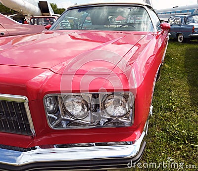 Close up, headlights of a shiny red classic car with focus on headlights and hood Stock Photo