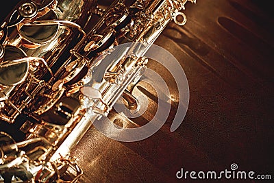 Close up and detailed view of a shiny keys of a golden saxophone lying on leather sofa. Musical instruments. Stock Photo